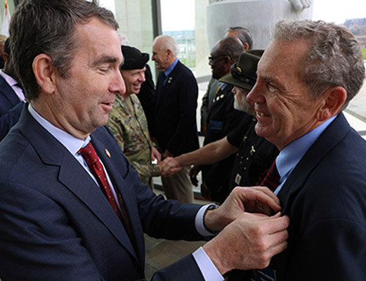 Governor Northam presents VWM volunteer and Navy veteran Chris Knaggs with Vietnam Veteran lapel pin.